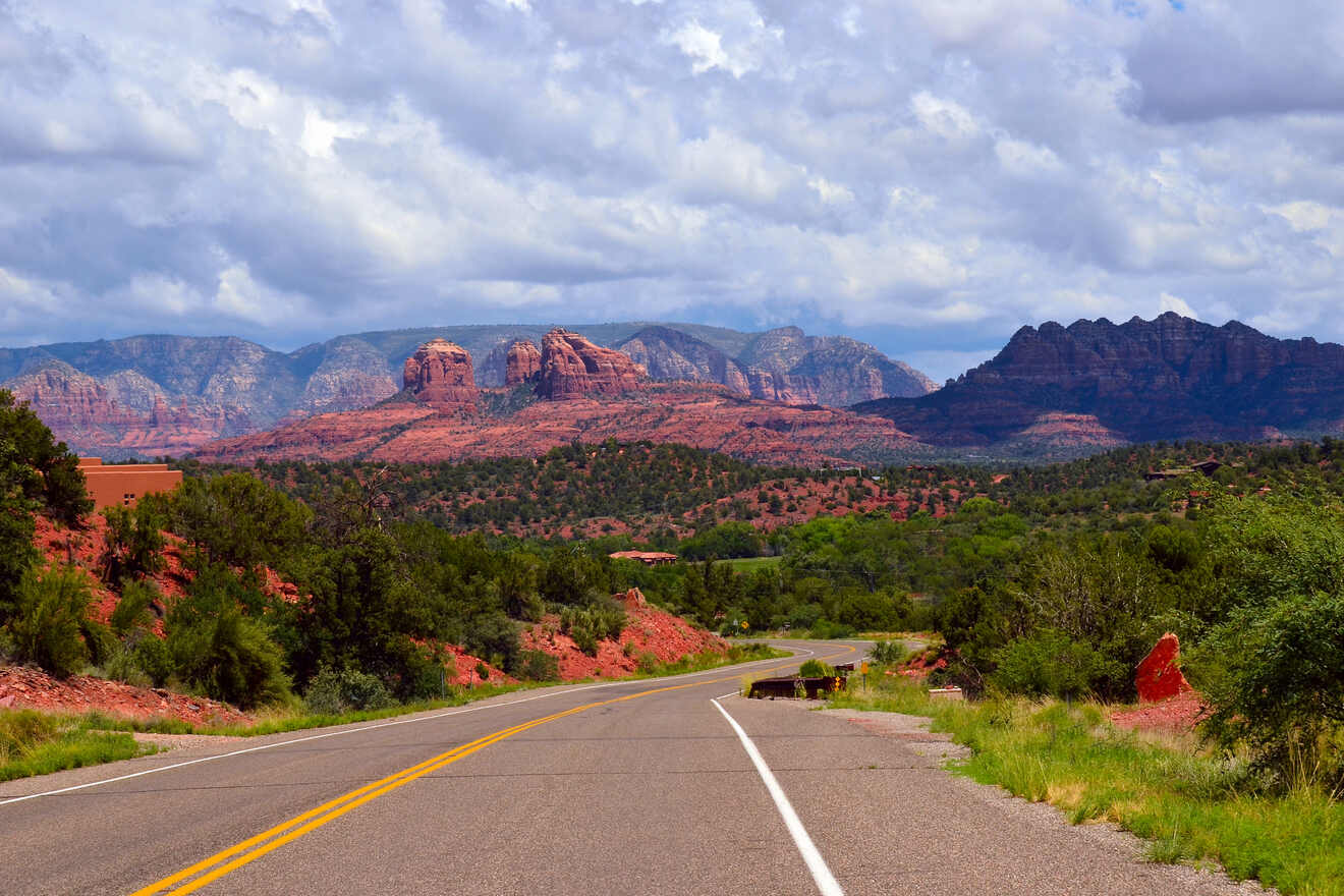 Scenic view of red rock formations in Sedona under a cloudy sky with a winding road leading towards the horizon
